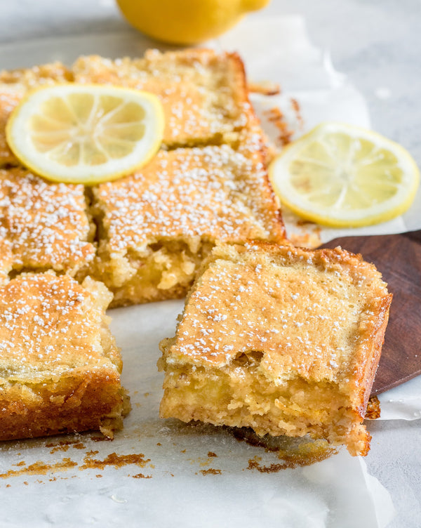Picture of freshly baked lemon bars topped with sifted powdered sugar and lemon slices