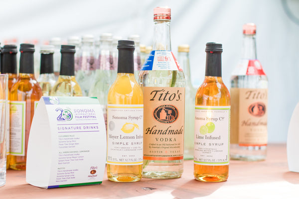 Photo of a festival booth with a variety of Sonoma Syrup's and a large bottle of Tito's Vodka for the Sonoma International Film Festival.