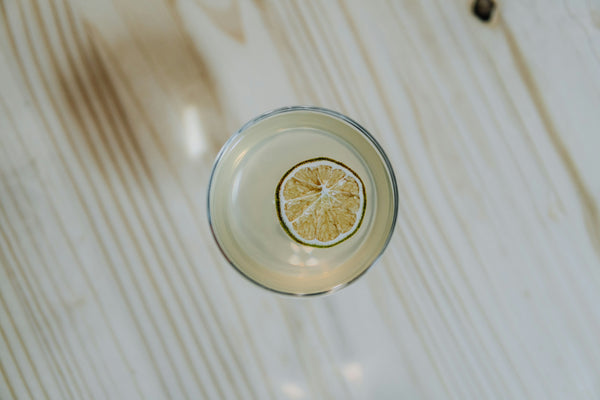 Picture of 2 glasses full of classic lime gimlet cocktail on marble table