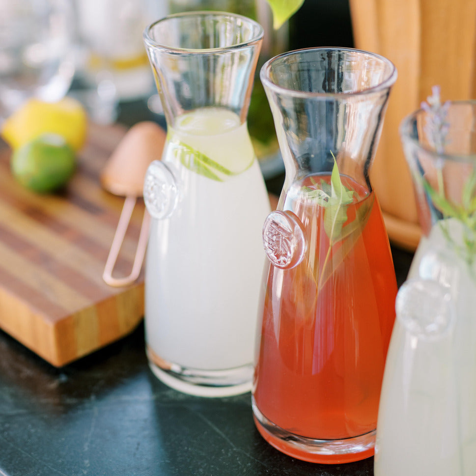 Three jars of infused lemonade on counter with citrus