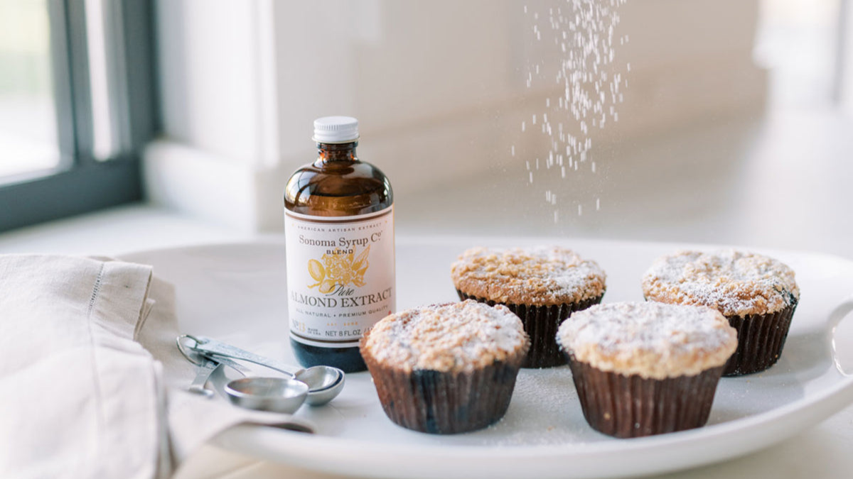 Pure almond extract bottle next to freshly baked cupcakes