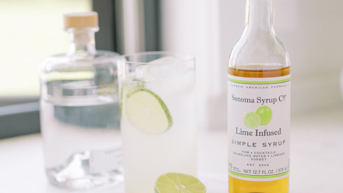 lime infused simple syrup next to cocktail class with limes